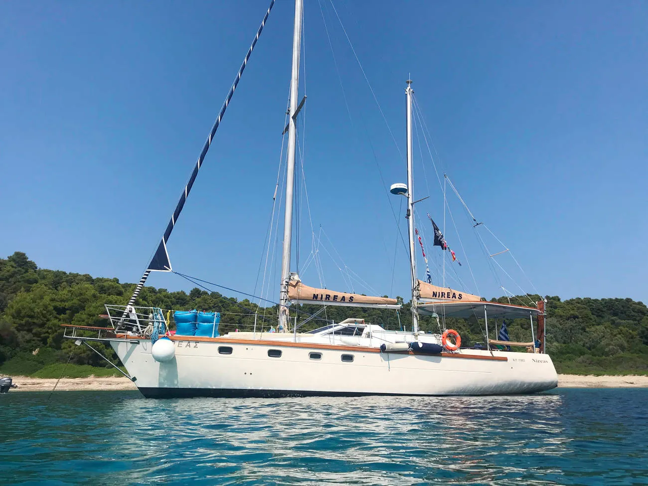 Nireas at anchor off a green shore