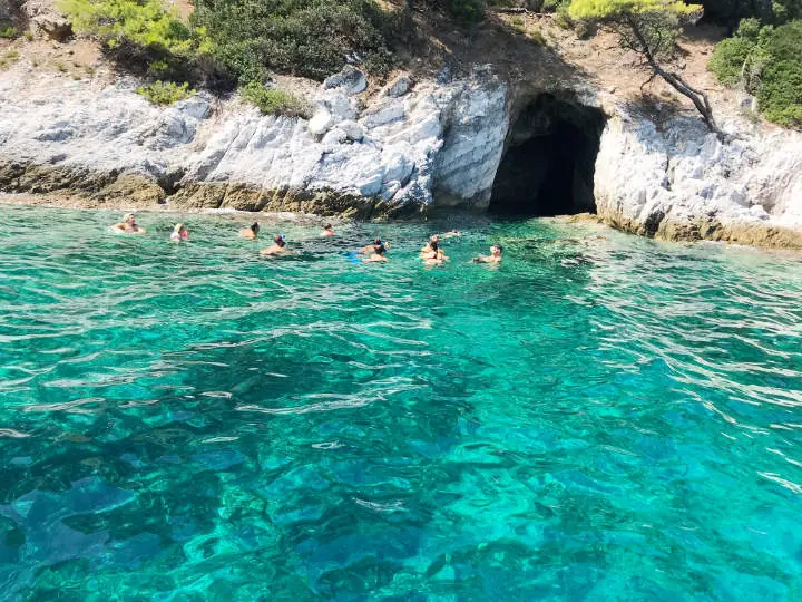 Swimmers by a sea cave