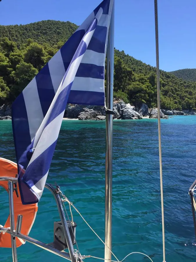 The Greek flag over the turquoise bay